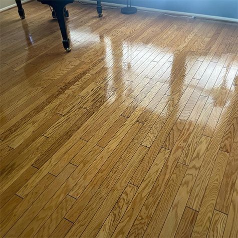 Shiny hardwood floor with bright window reflections and table legs in the corner.
