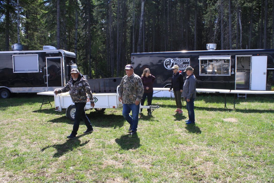 A group of people are walking in a field in front of a food truck.