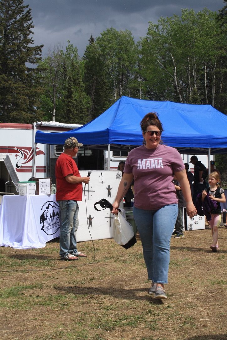 A woman wearing a purple shirt that says mama is walking in a field.