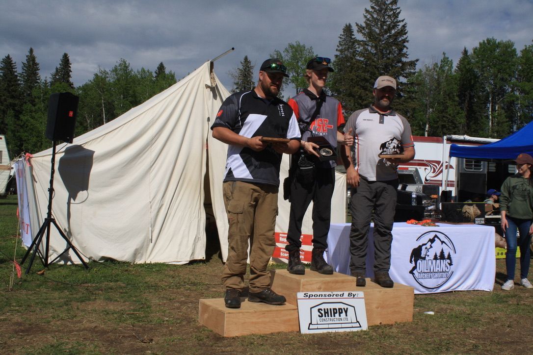 Three men are standing on a podium in front of a tent