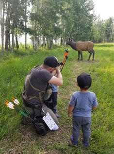 A man and two children are looking at a deer in a field.