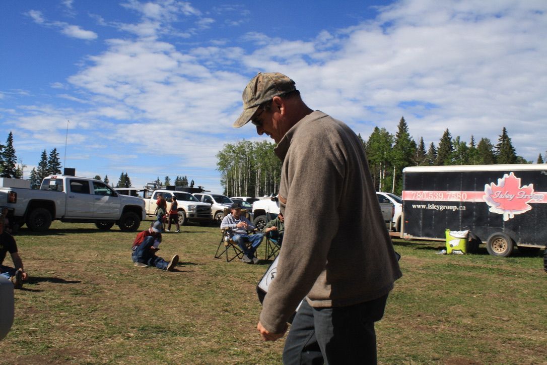 A man standing in a field with a trailer that says ' canadian ' on it