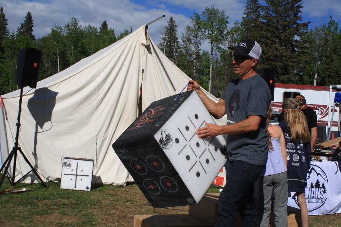 A man is holding a large cube in front of a tent