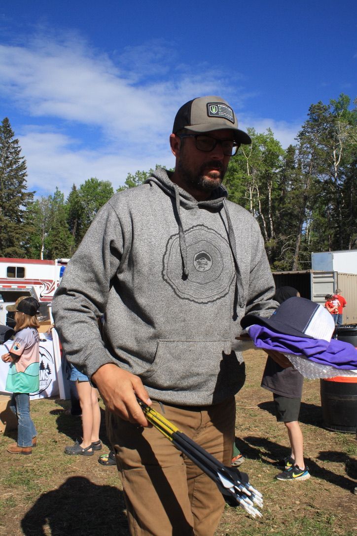 A man wearing a hat and a hoodie is holding a pair of tongs.