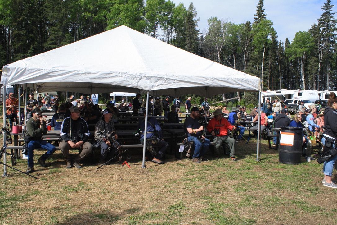 A group of people sitting under a tent in a field