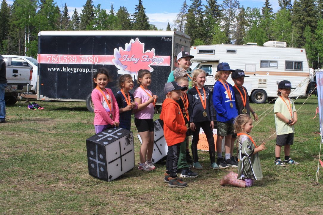A group of children are standing in a field in front of a trailer.