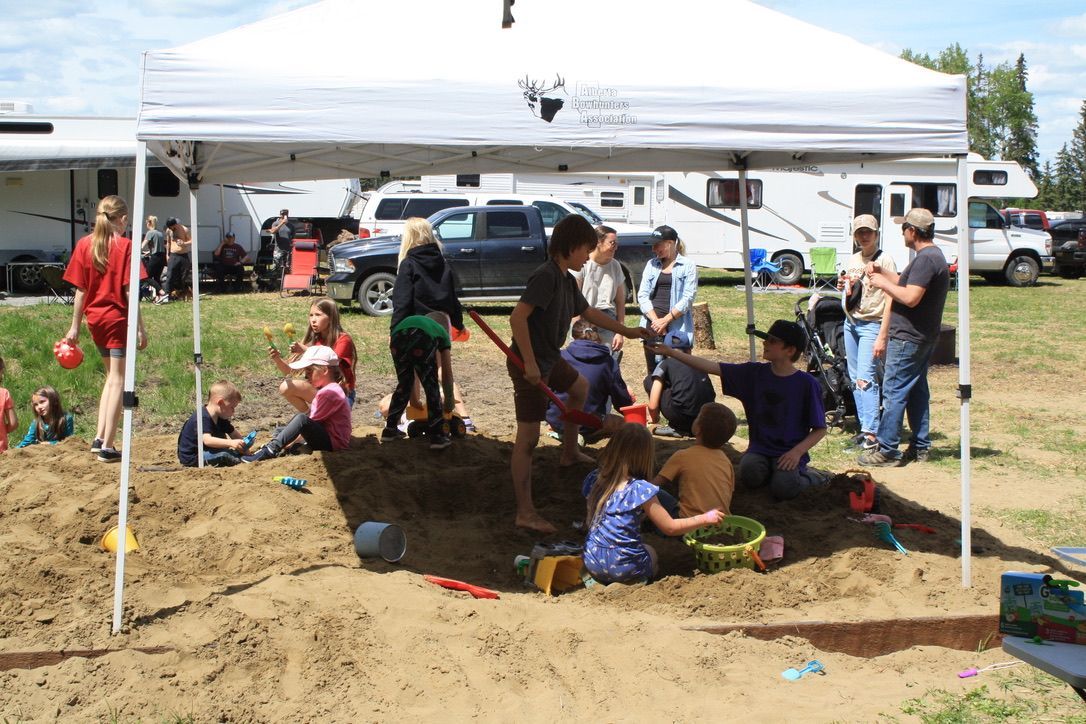 A group of children are playing in a sandbox under a tent.