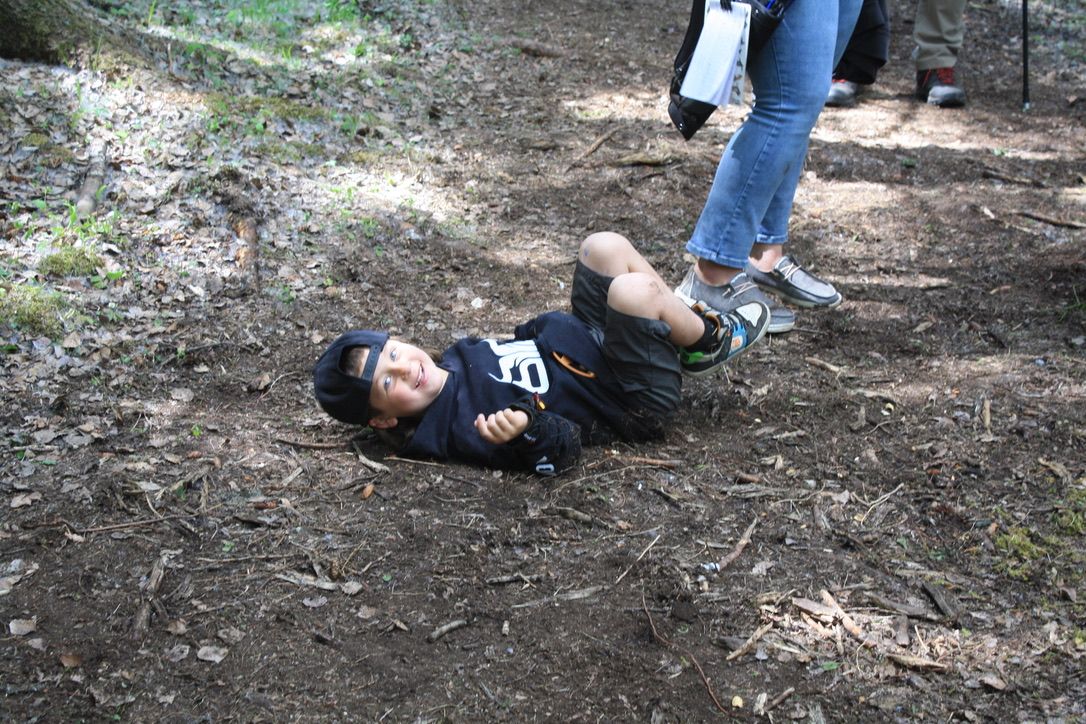 A young boy is laying on the ground in the woods.
