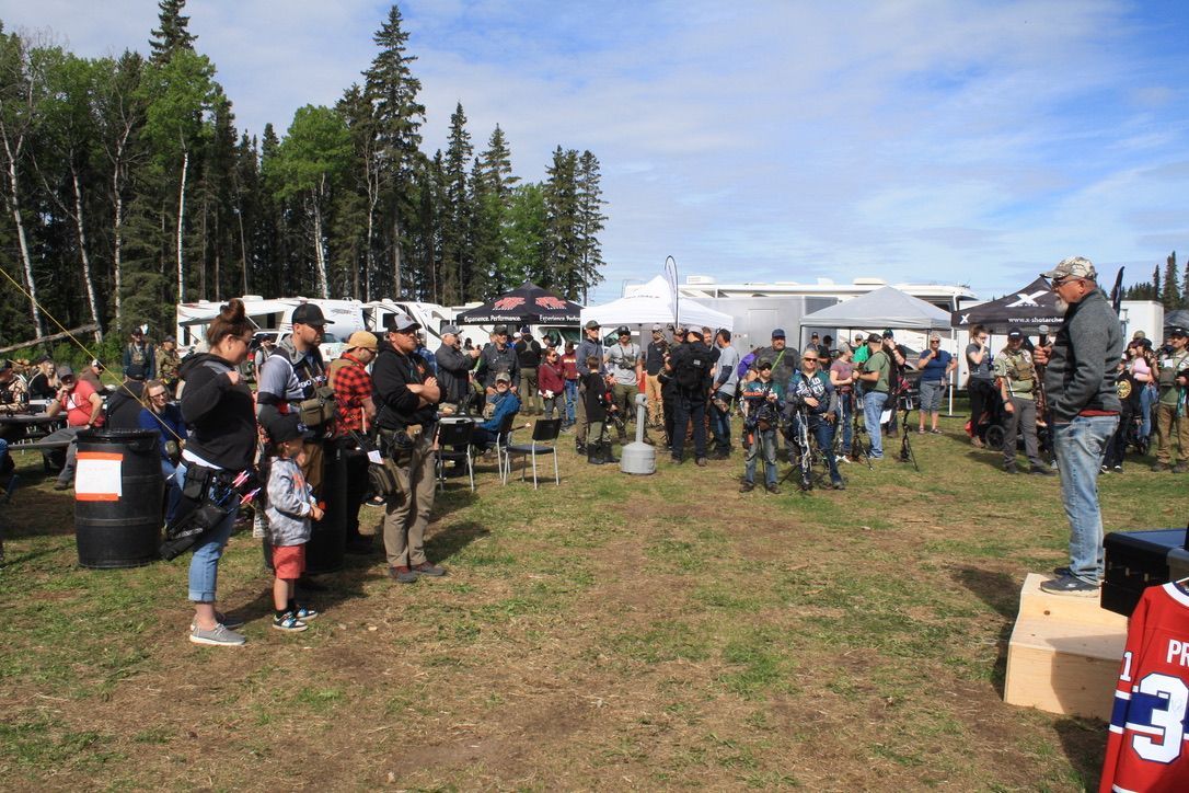 A man is standing in a field talking to a crowd of people.