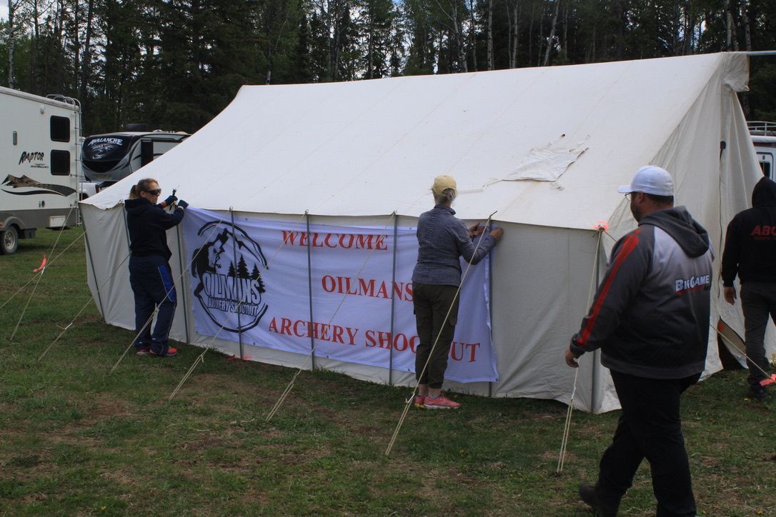 A group of people are setting up an archery shop tent