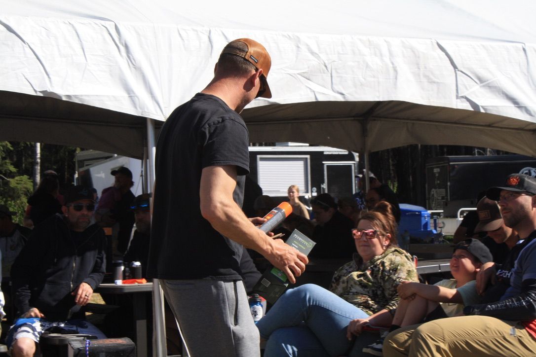 A man is standing in front of a group of people under a tent.