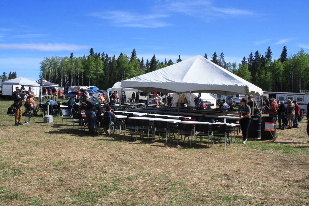 A group of people are gathered under a tent in a field.