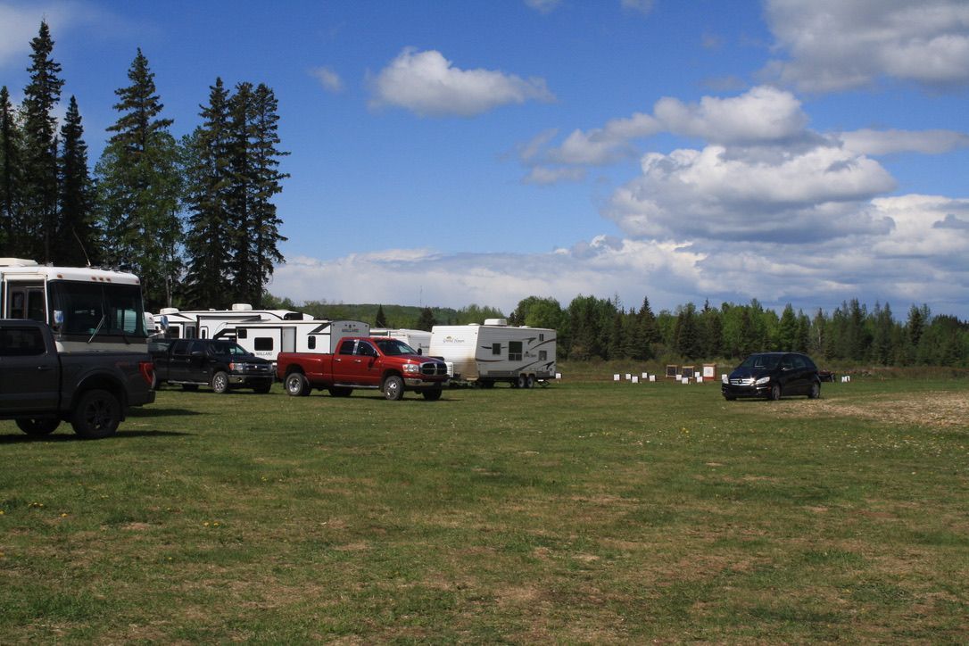 A row of rvs are parked in a grassy field