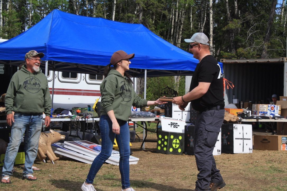 A man and a woman are shaking hands in front of a blue tent.