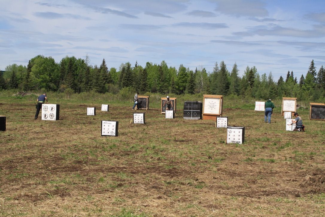 A group of people are standing in a field with archery targets