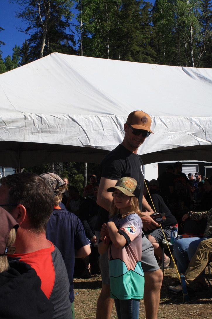A man is holding a little girl in his arms in front of a white tent.