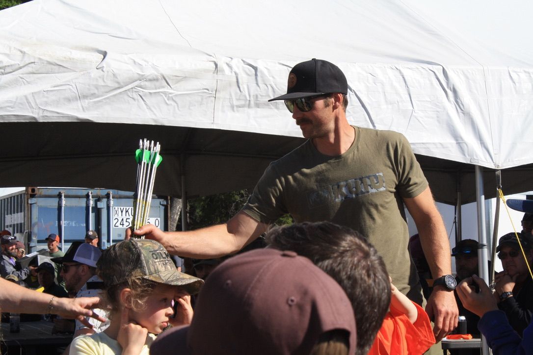 A man is holding a trophy in front of a group of people under a tent.