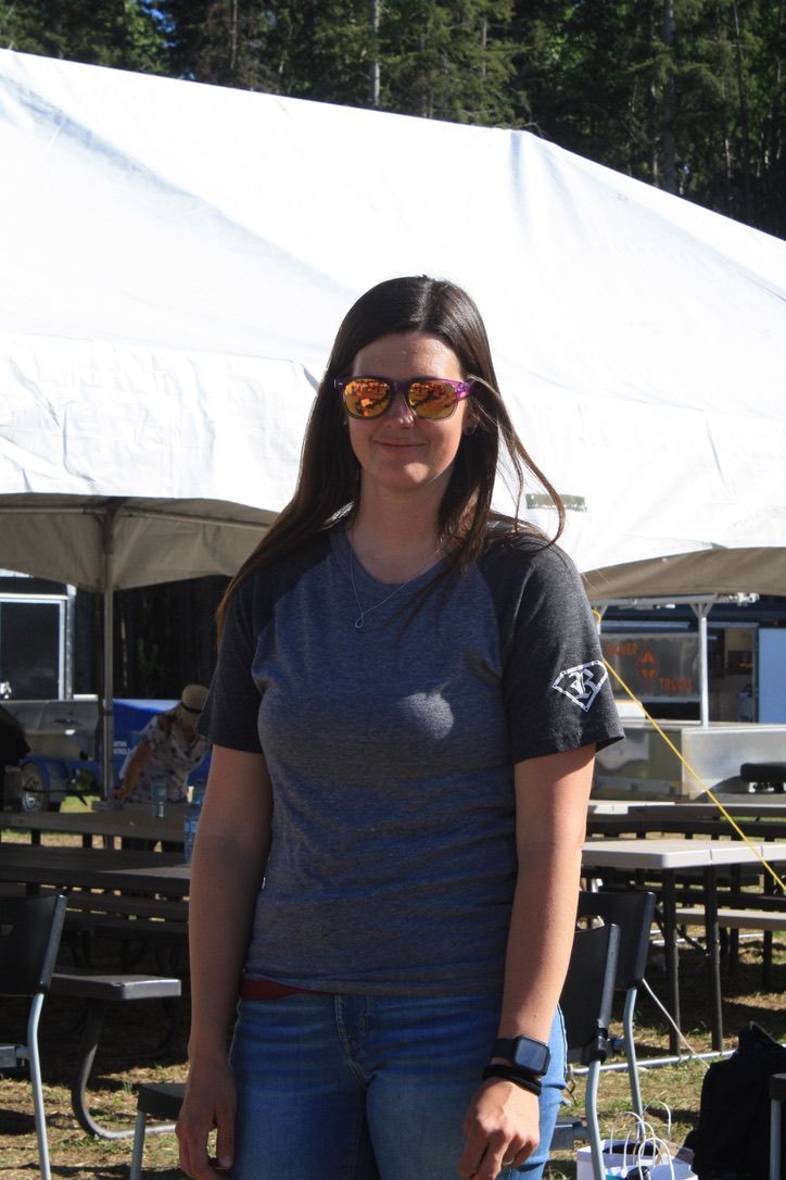 A woman wearing sunglasses stands in front of a white tent