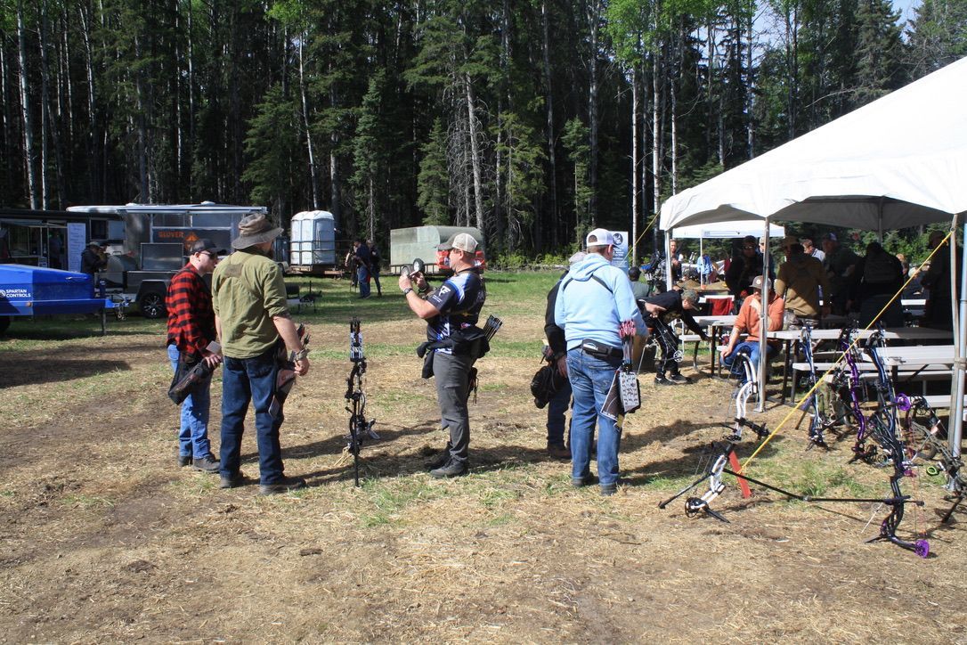 A group of people are standing in a field under a tent.