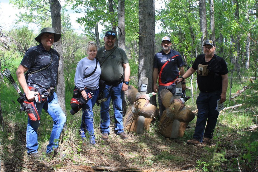A group of people are posing for a picture in the woods.