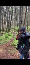A man and a woman are standing in the middle of a forest.