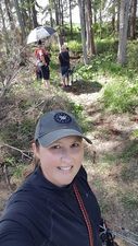 A woman in a hat is taking a selfie in the woods.