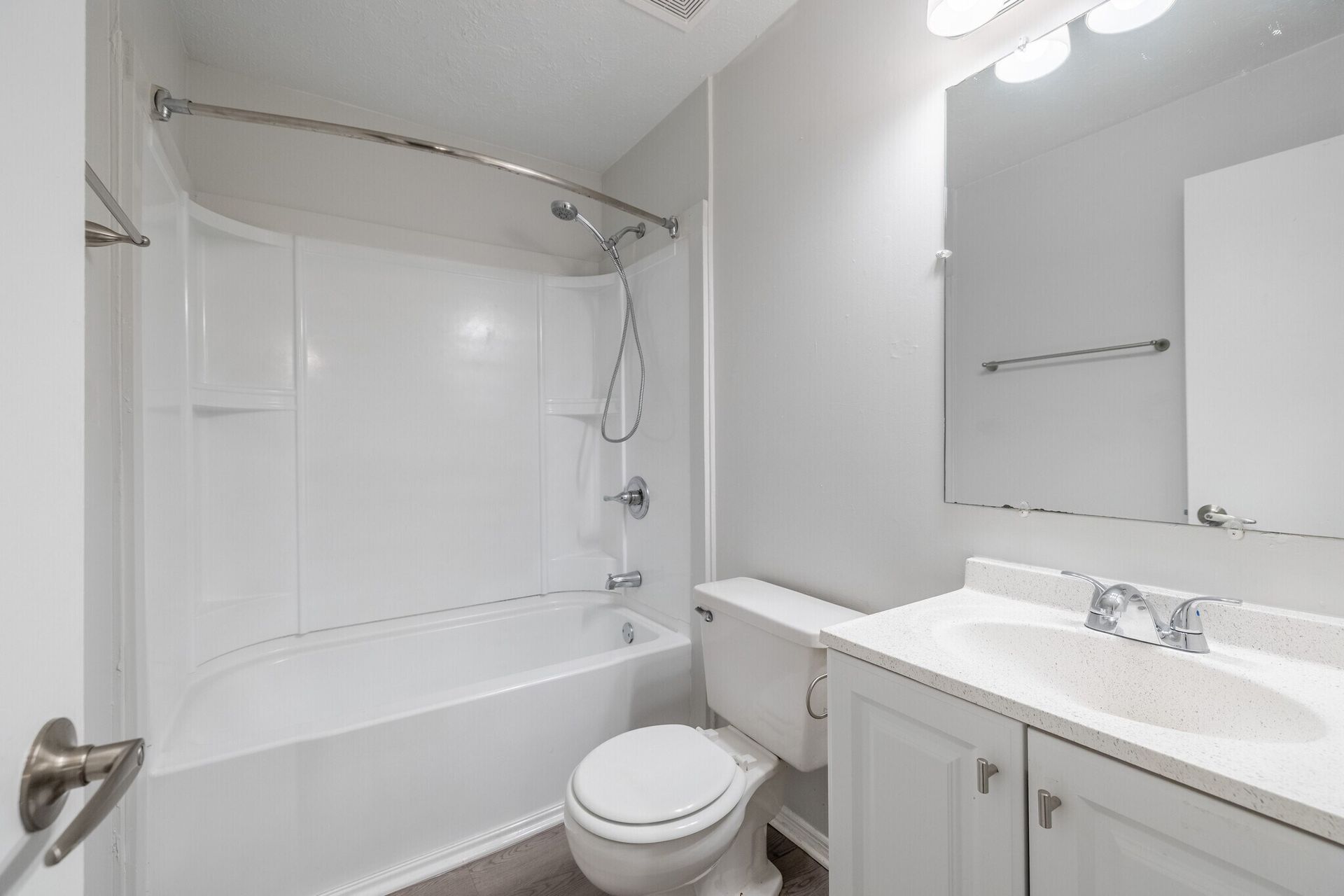 White bathroom with tub/shower, toilet, vanity, and a large mirror at Glastonbury Woods Apartments.