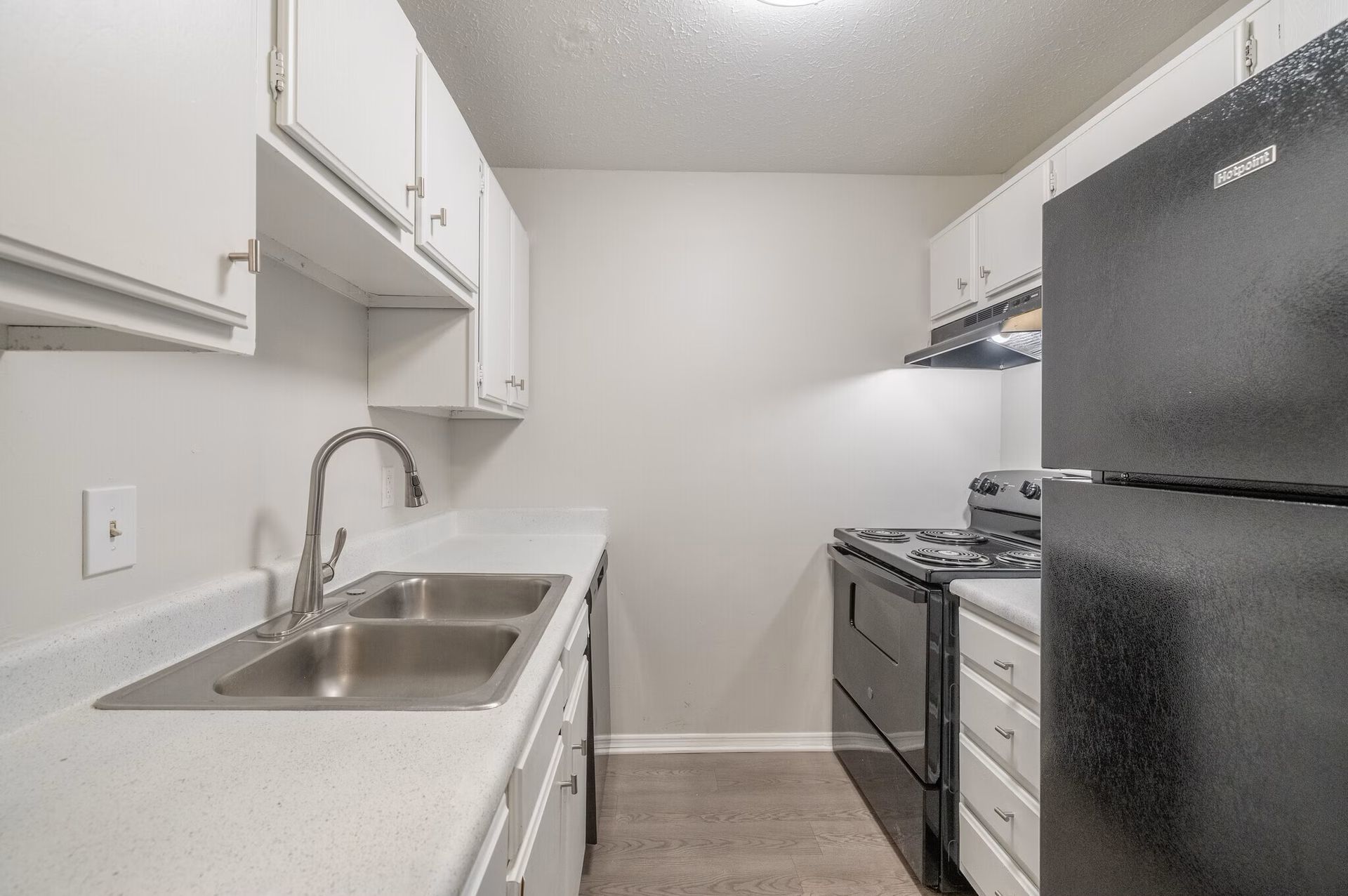 Glastonbury Woods Apartments Kitchen with white cabinets, light countertops, and black appliances.
