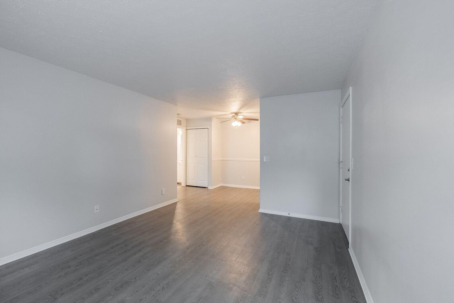 Empty apartment interior with grey flooring, white walls, and an open doorway at Glastonbury Woods Apartments.