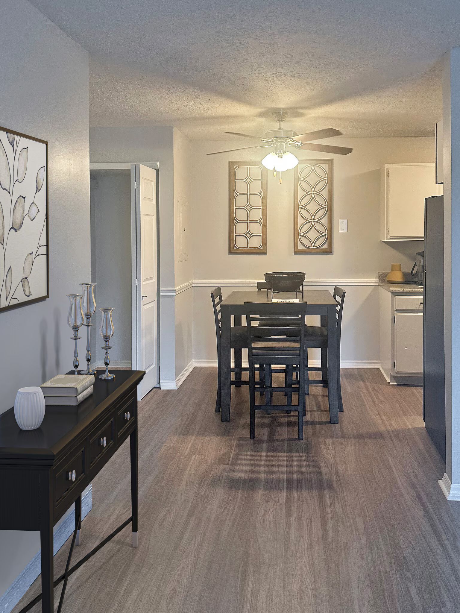 Interior of a dining area with a table, chairs, artwork, and a kitchen at Glastonbury Woods Apartments