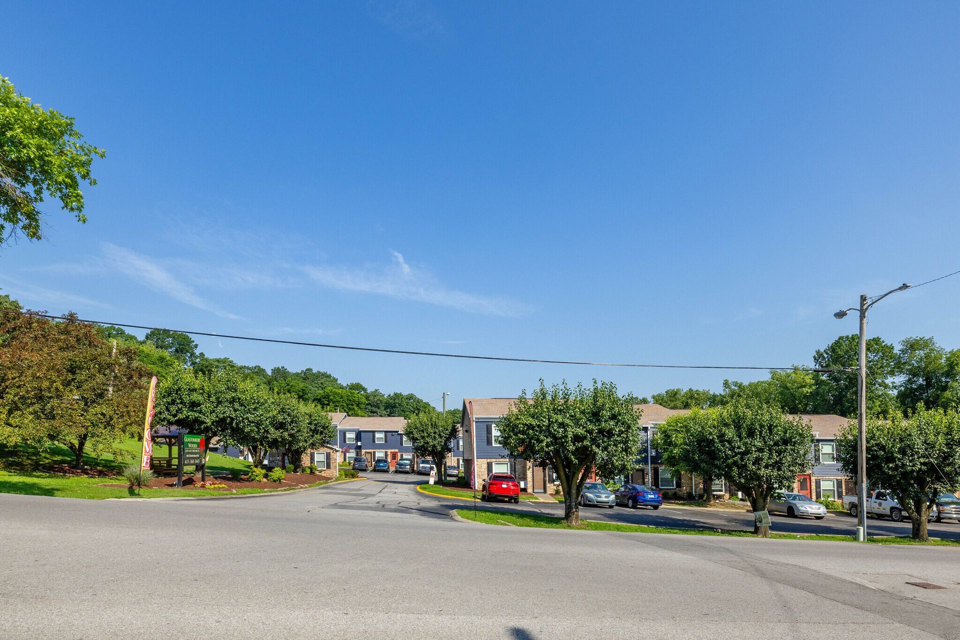 Glastonbury Woods Apartment buildings with driveways and parked cars, under a clear blue sky.