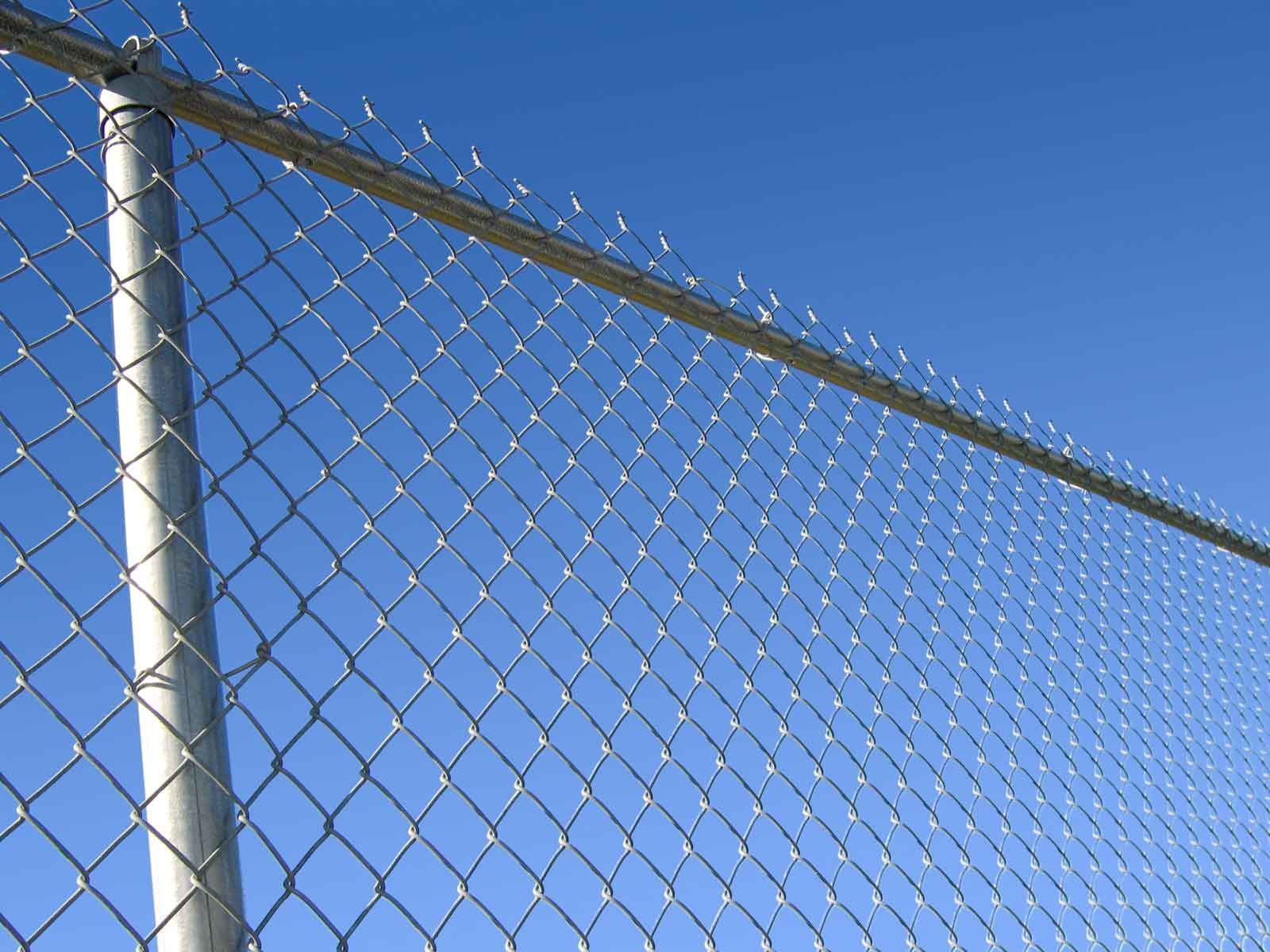 Chain-link fence against a clear blue sky.