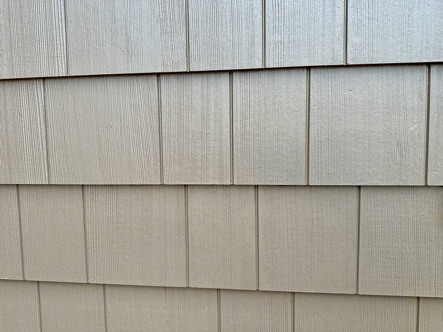 Close-up of gray composite shake siding, with textured, overlapping panels.