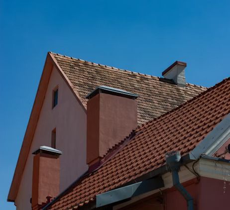 Red-tiled rooftops and chimneys against a clear blue sky.