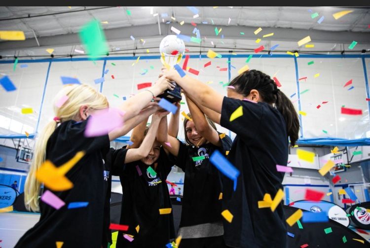 Four young girls raising a trophy for the Mandeville Soccer Club Futsal league