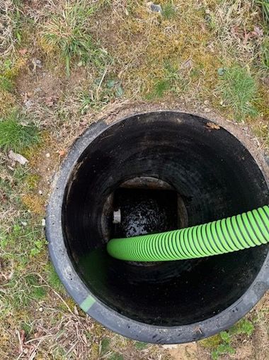 Worker installs green septic tank lid in garden soil.