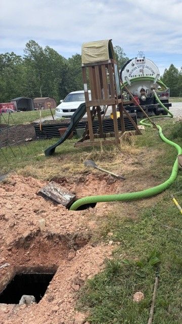 Worker cleaning a lawn septic tank with a vacuum truck in a suburban yard