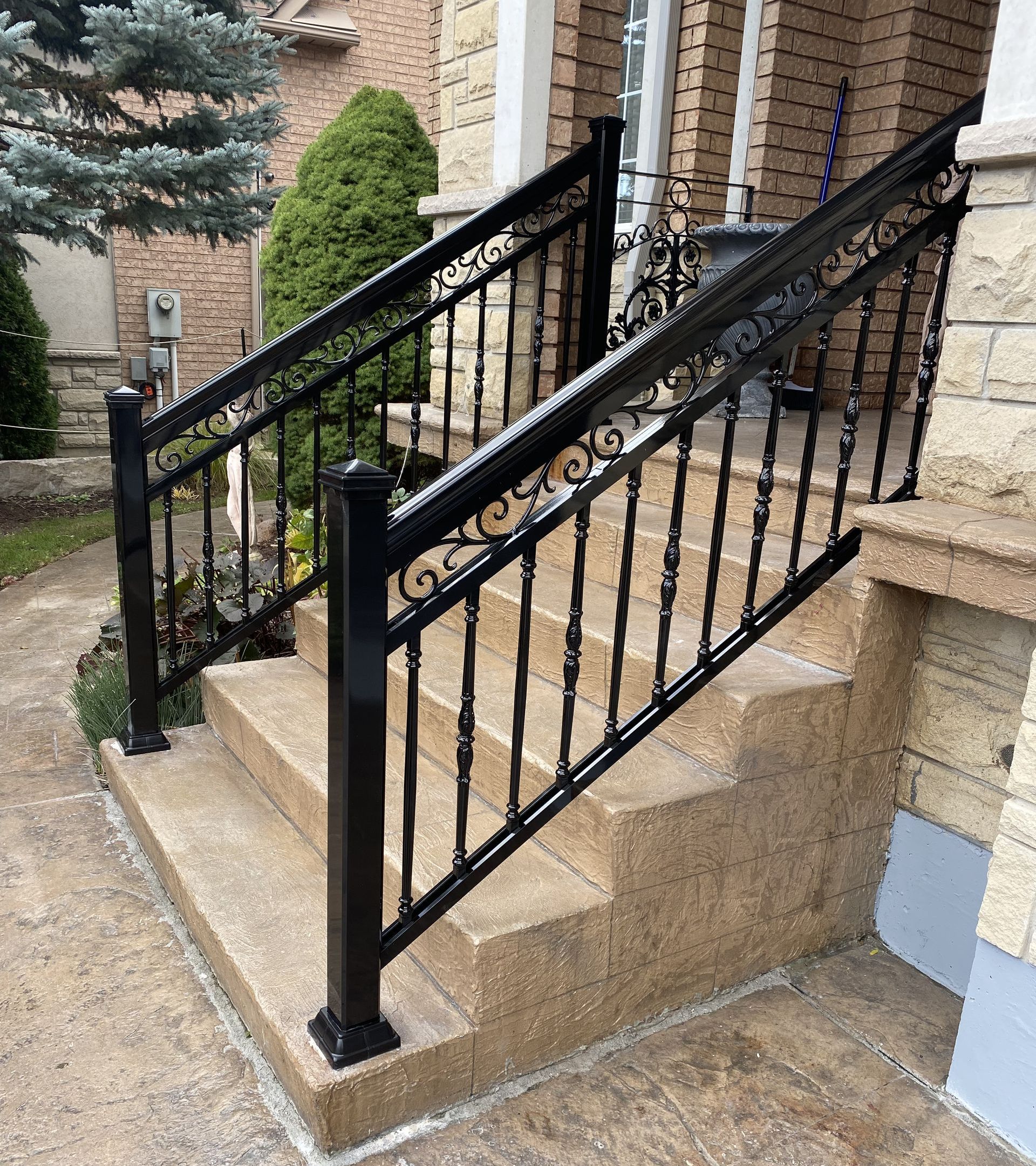 A black wrought iron railing is sitting on top of a set of stairs.