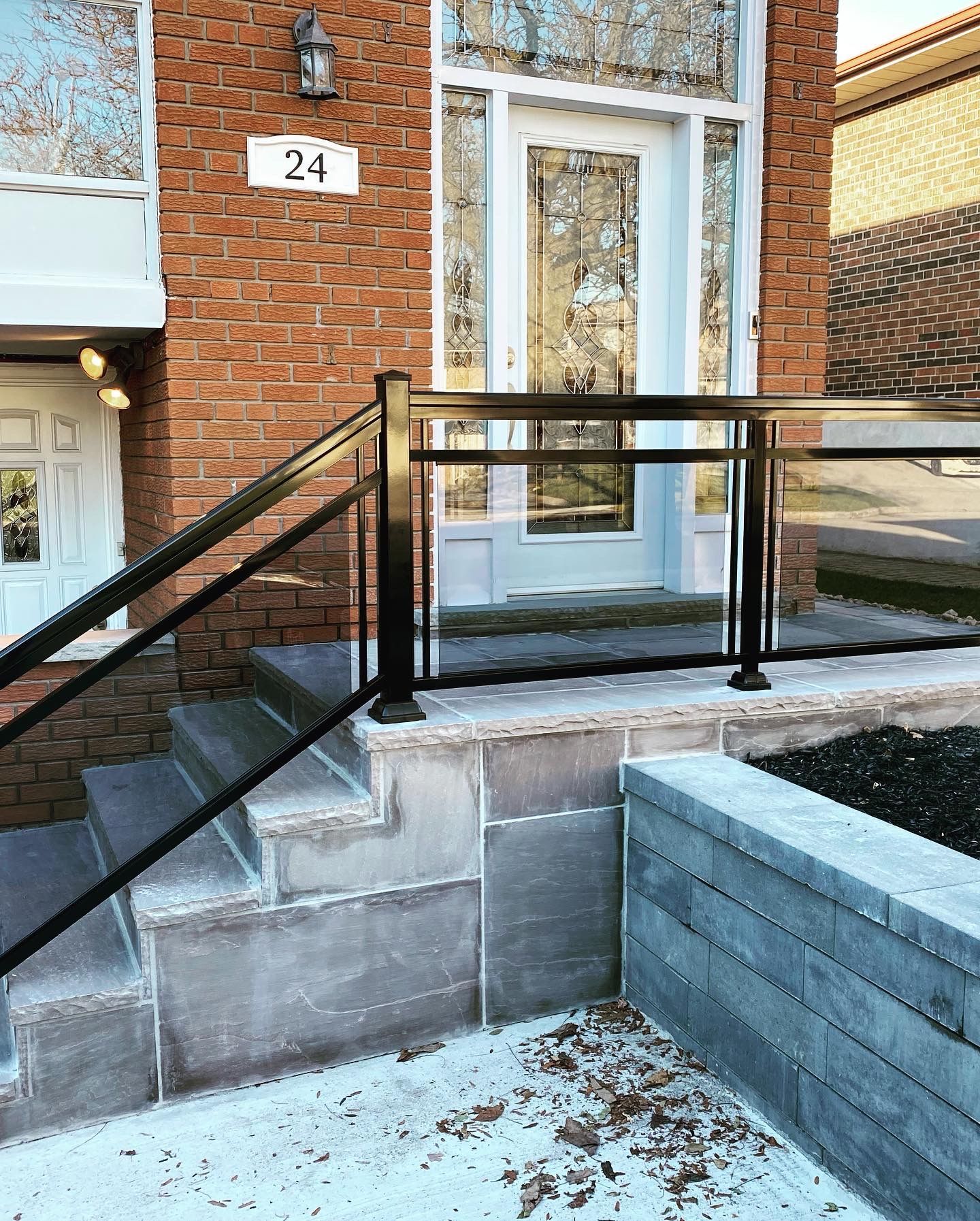 A brick house with a glass railing and stairs leading up to the front door.