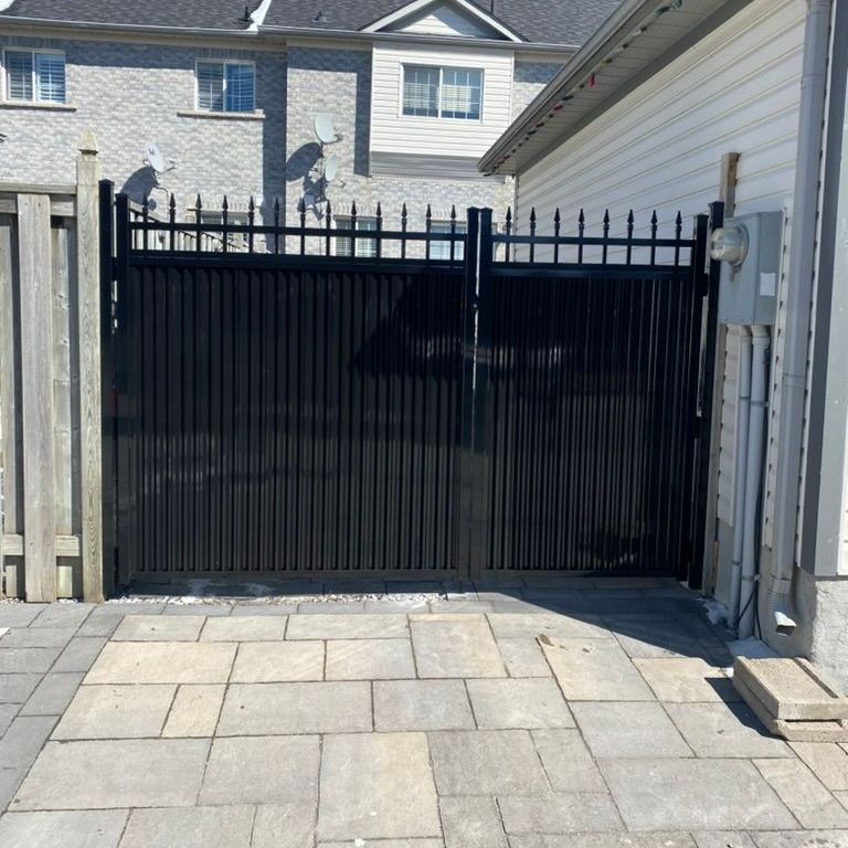 A black gate is sitting in front of a house.
