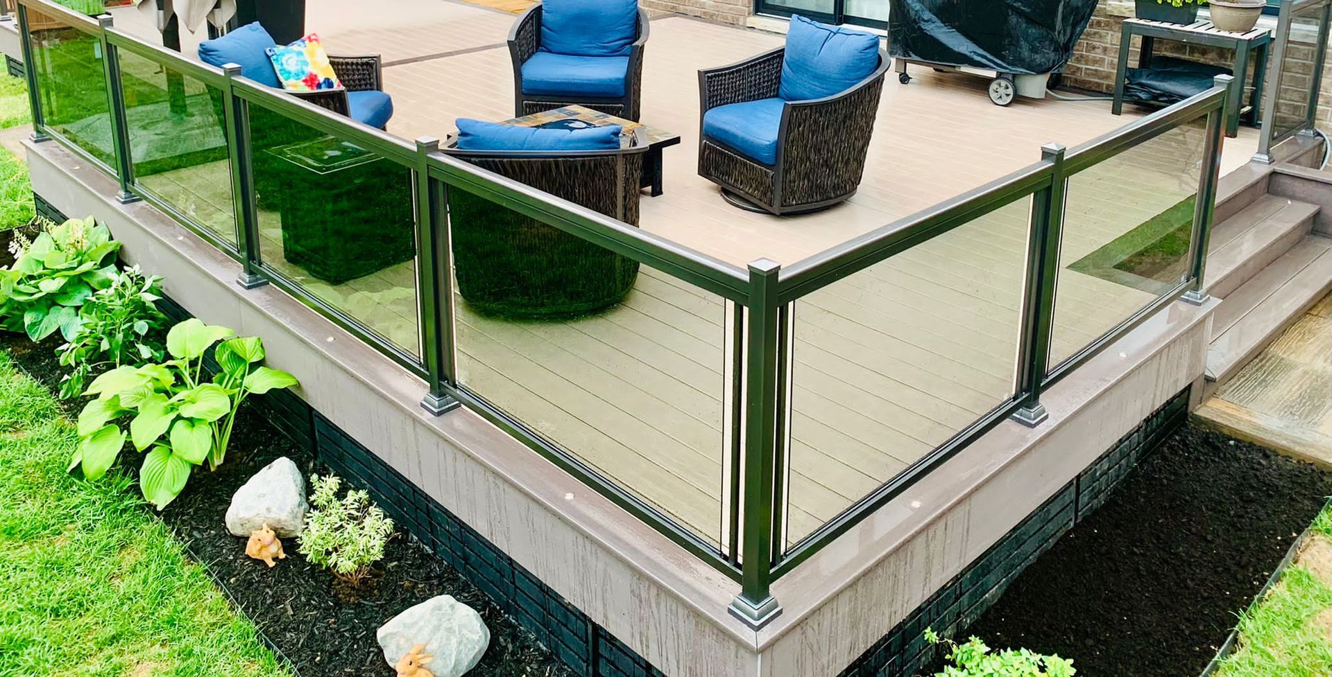 A deck with a glass railing and furniture on it.