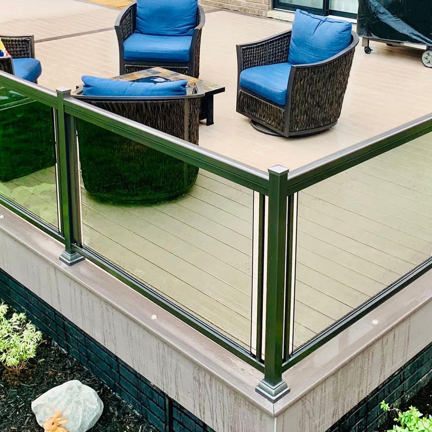 A deck with wicker furniture and a glass railing