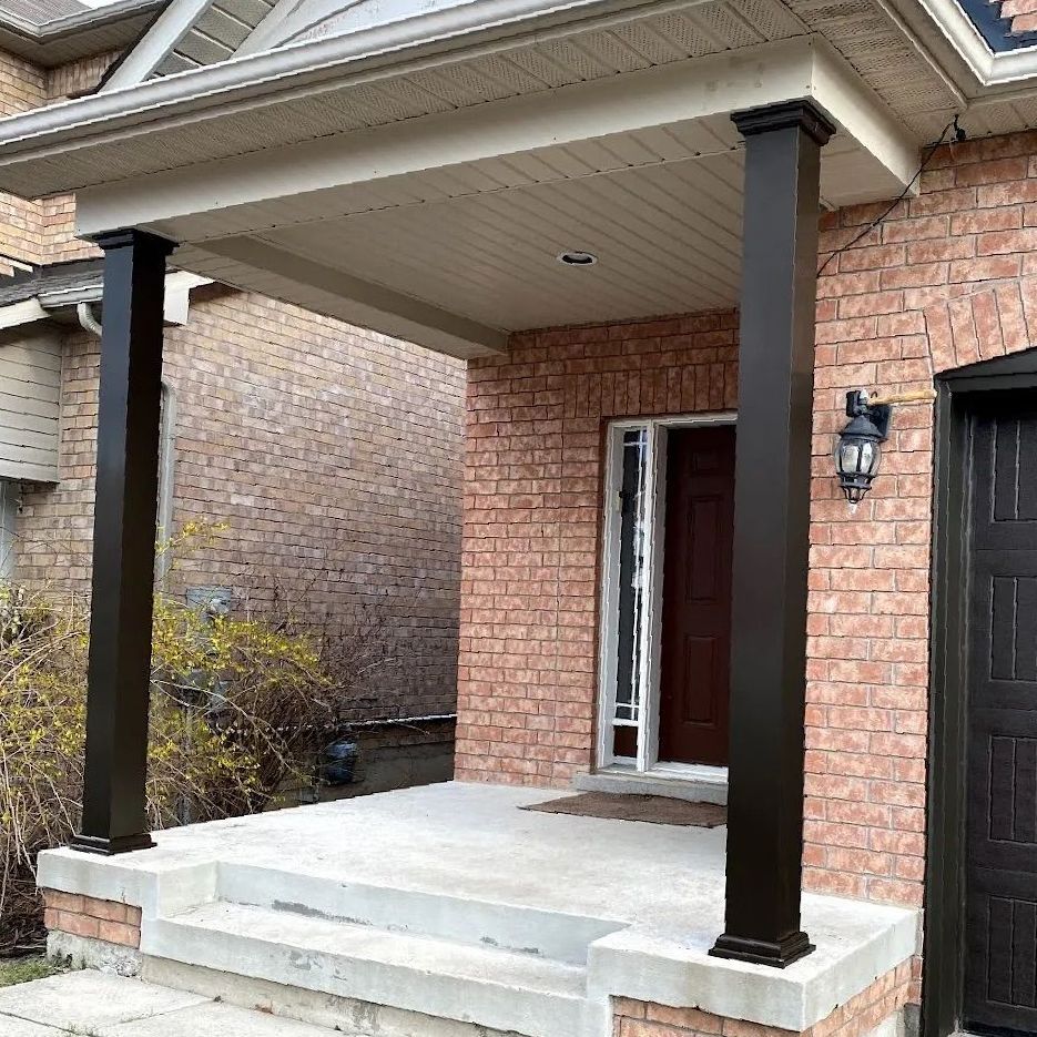 A brick house with a porch and black pillars