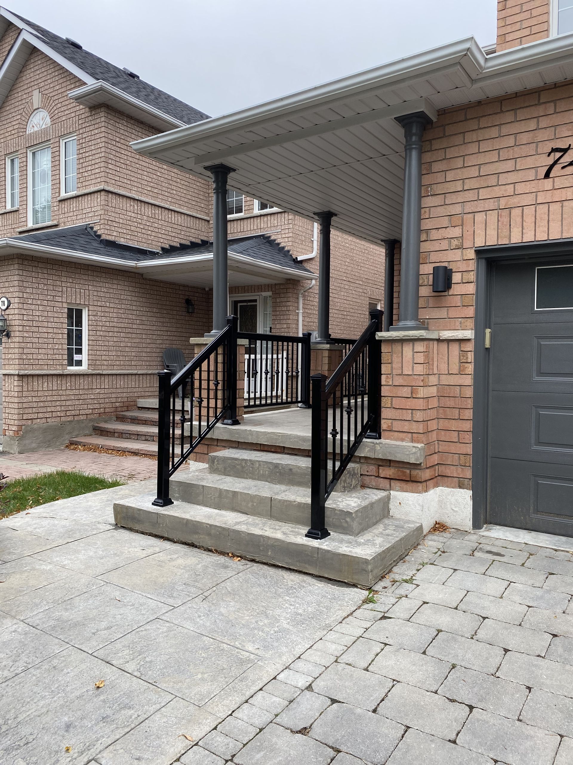 A brick house with a black garage door and stairs