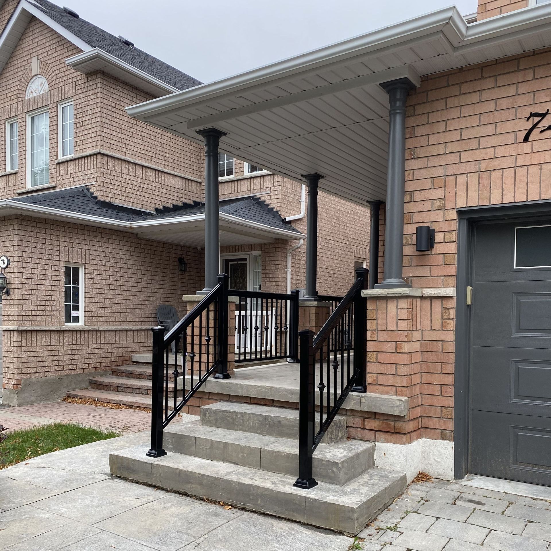A brick house with a black garage door and stairs