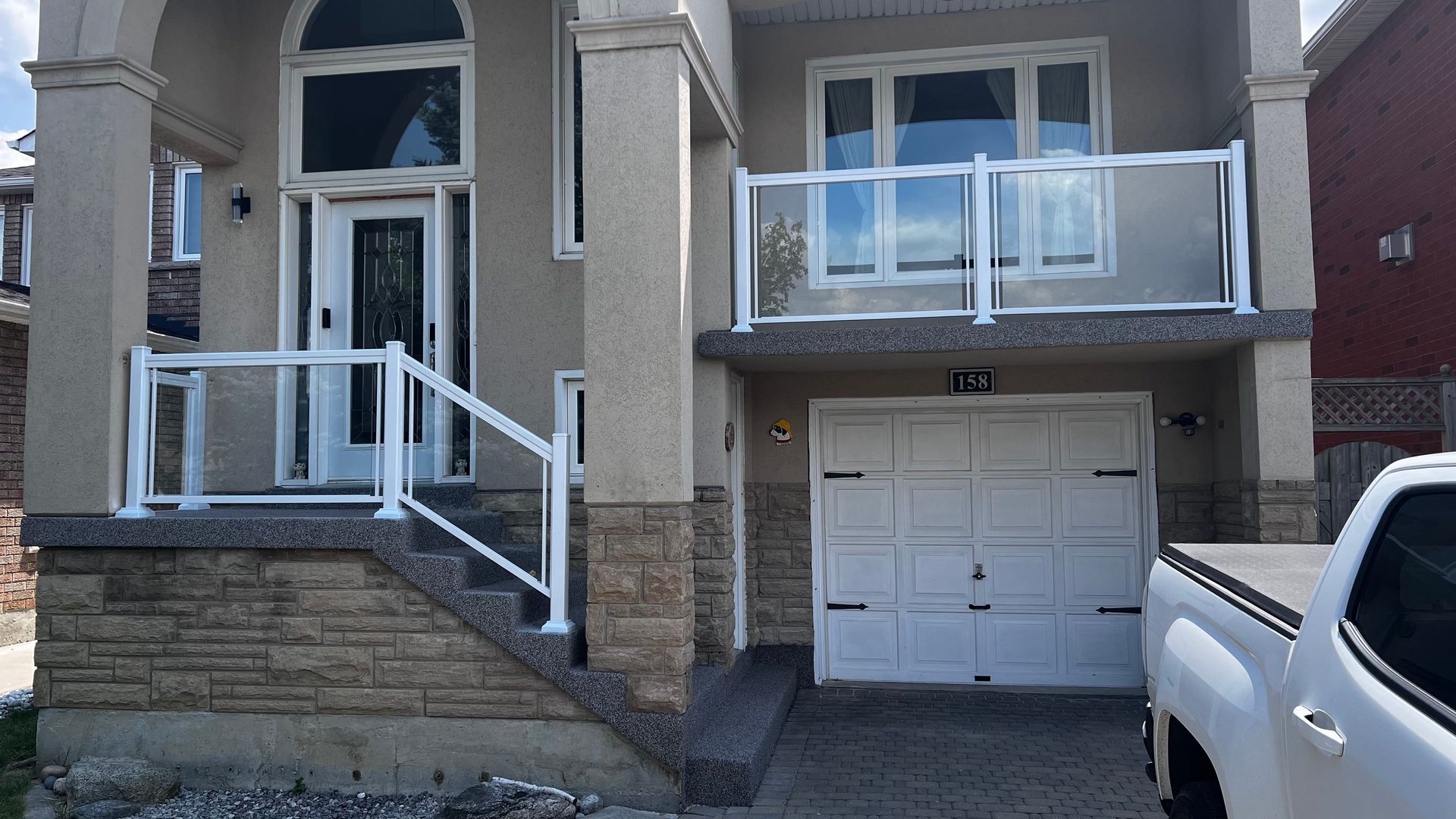 Two-story house with white aluminum and clear glass railings.