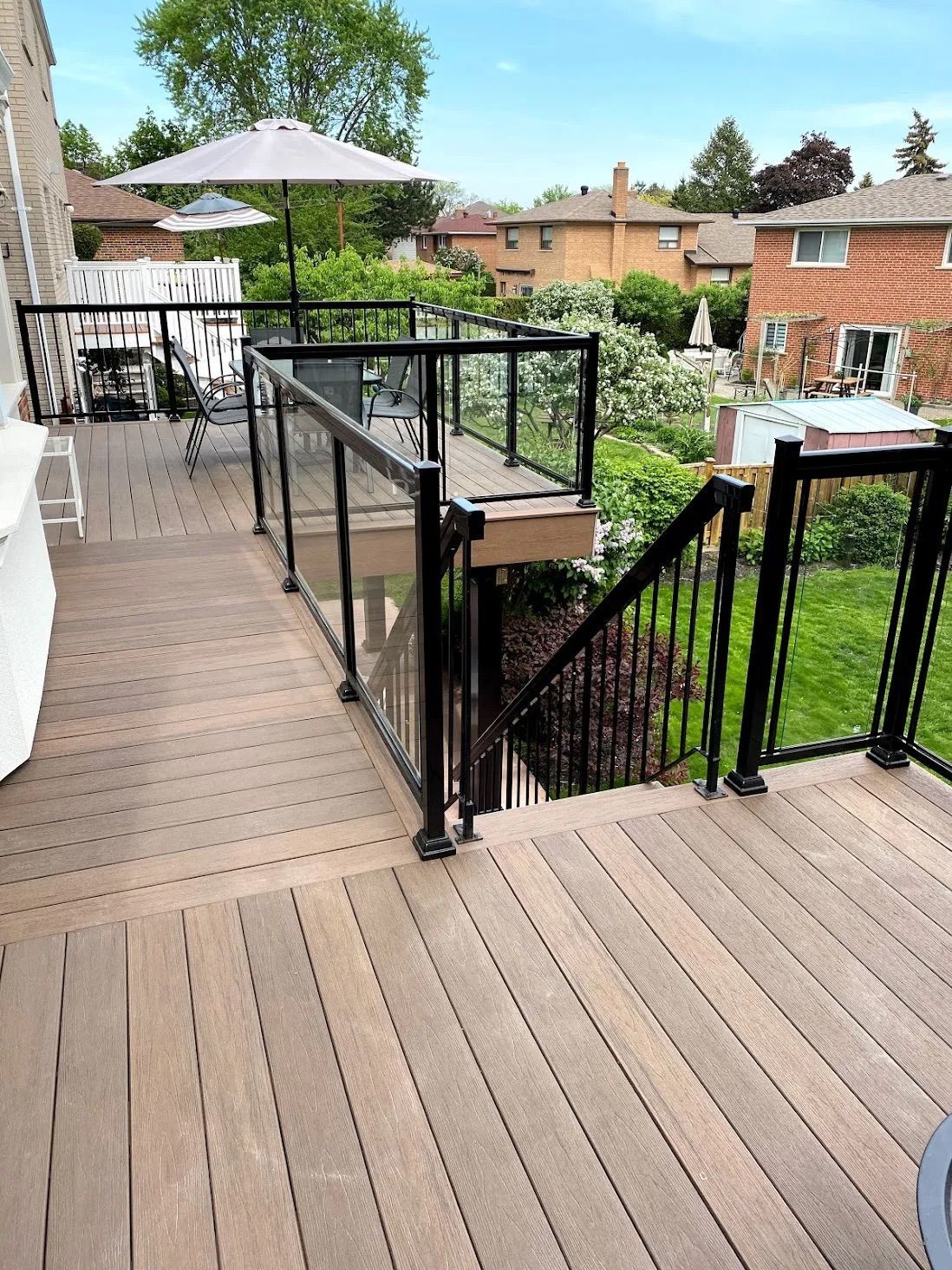 A wooden deck with a black railing and stairs leading up to it.