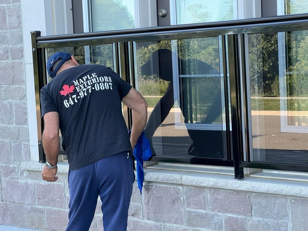 A man in a black shirt is cleaning a window.