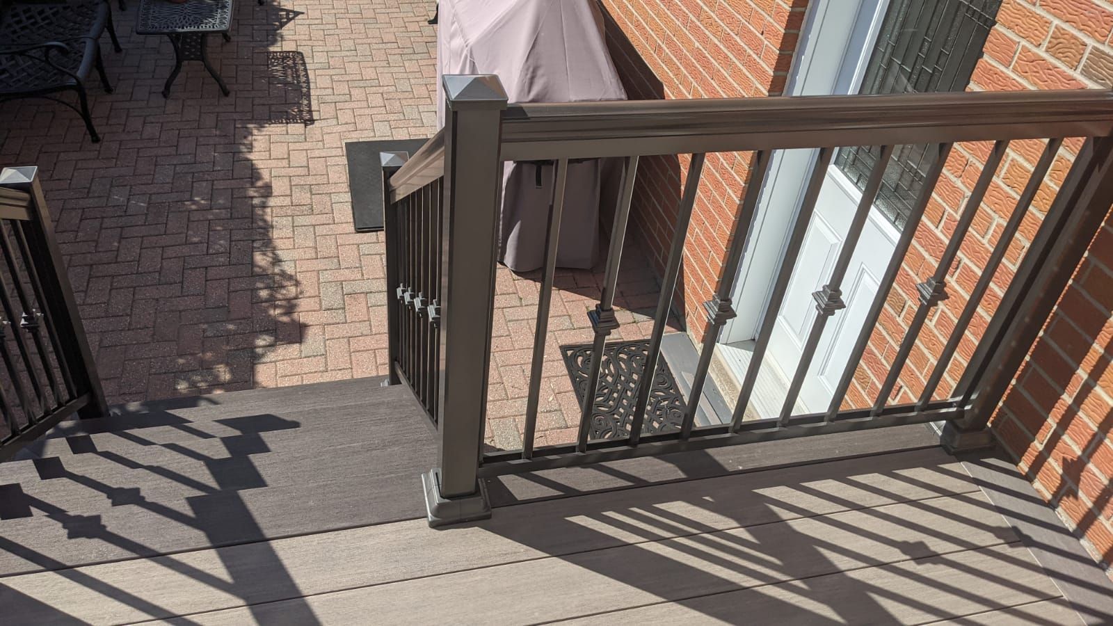 A balcony with a railing and stairs leading up to a brick building.