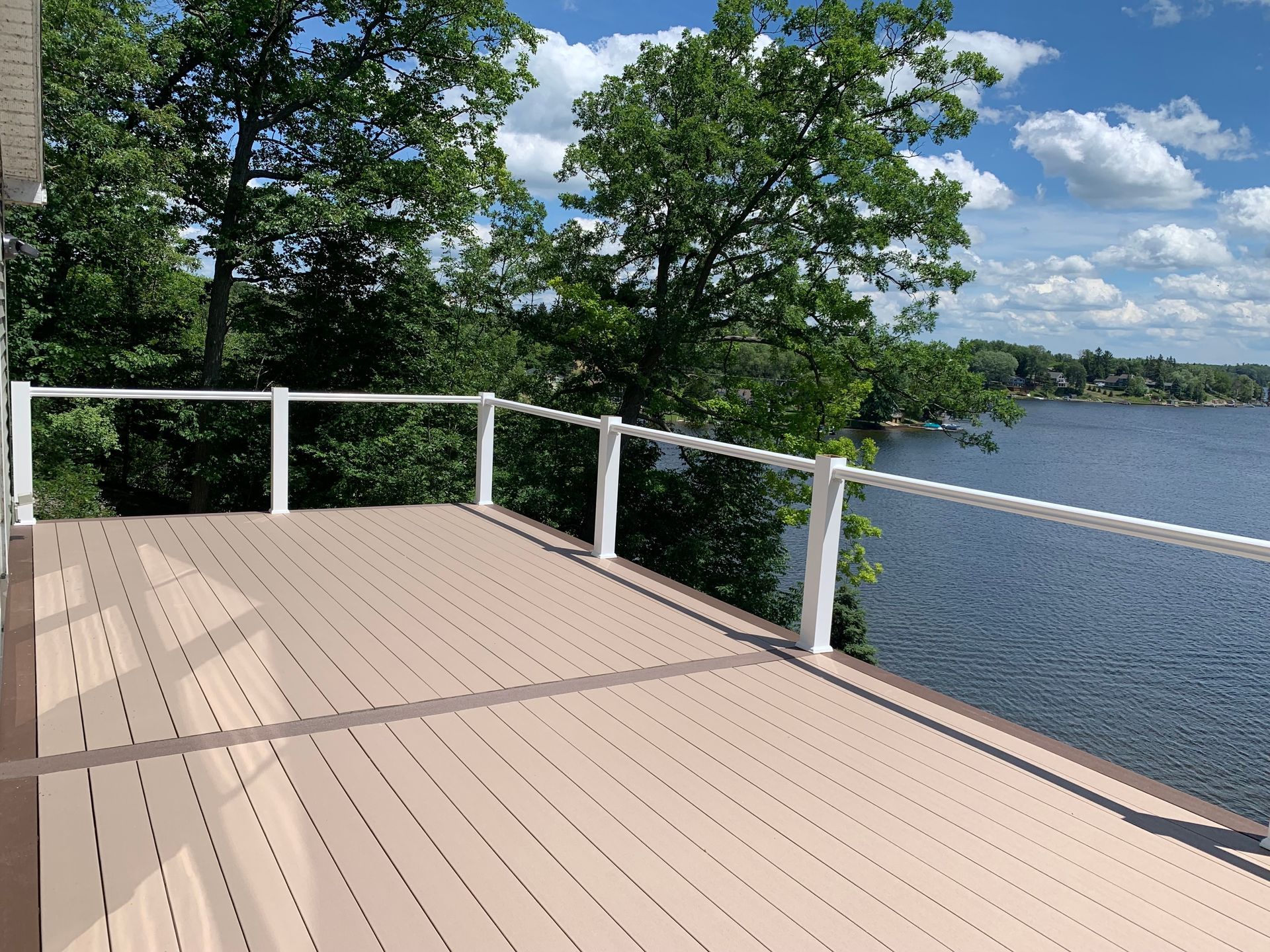A deck overlooking a lake with trees in the background